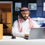 traditional middle eastern entrepreneur using wireless using his wireless headphones laptop
