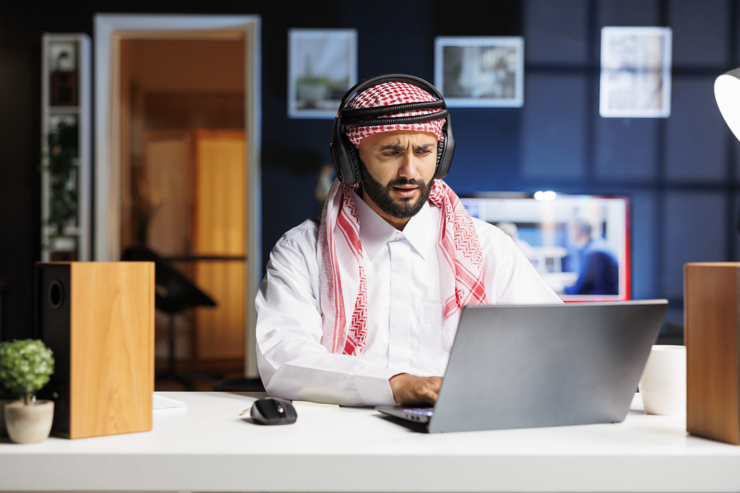 traditional middle eastern entrepreneur using wireless using his wireless headphones laptop